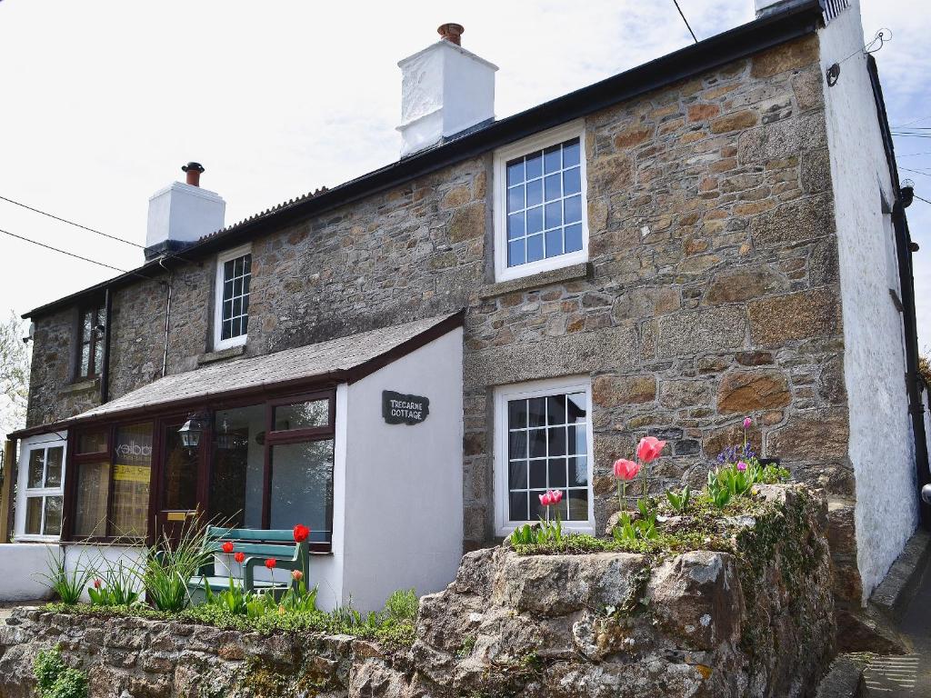 a stone building with a bench in front of it at Trecarne Cottage in Saint Cleer