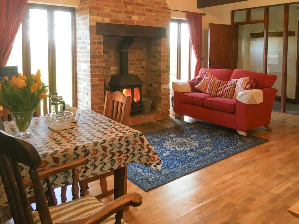 a living room with a red couch and a fireplace at The Coach House in Tytherton Lucas