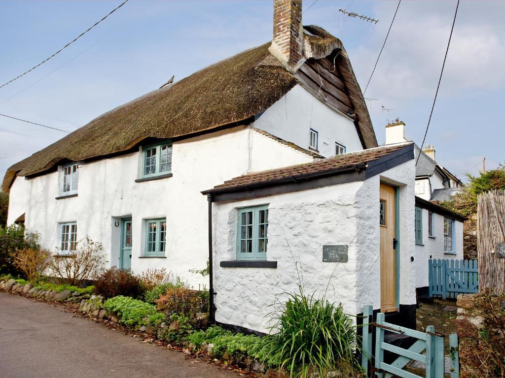 un vecchio cottage bianco con tetto di paglia di Sea Glass Cottage a Dawlish