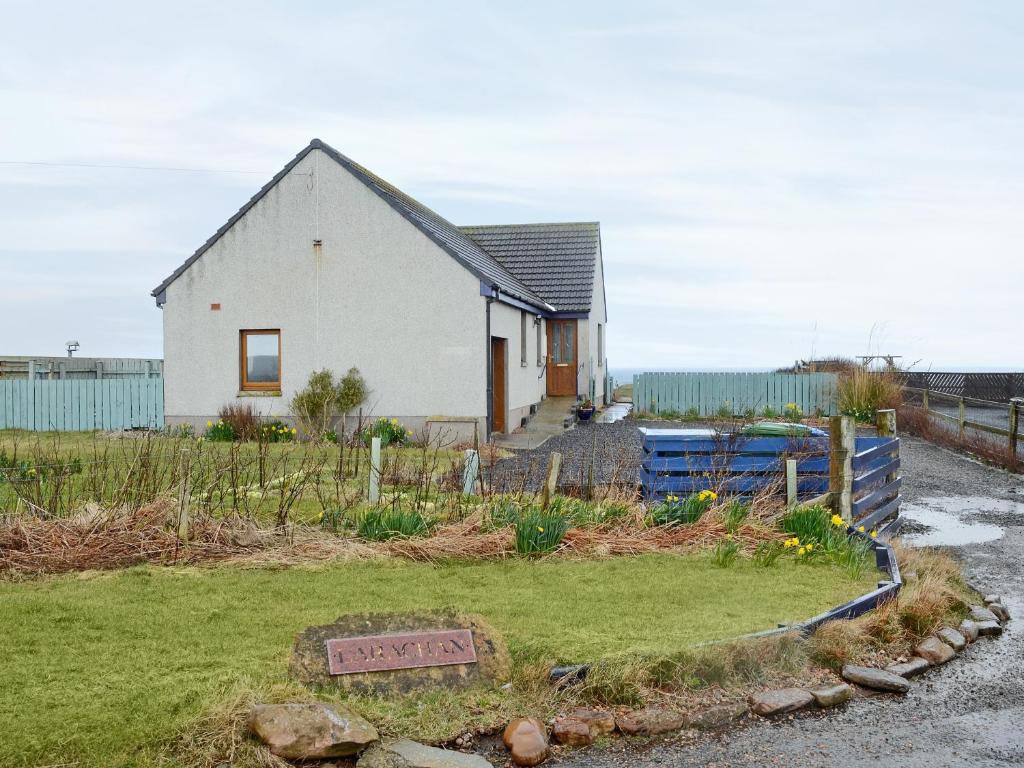 a white house with a fence and a yard at Larachan in Scarfskerry