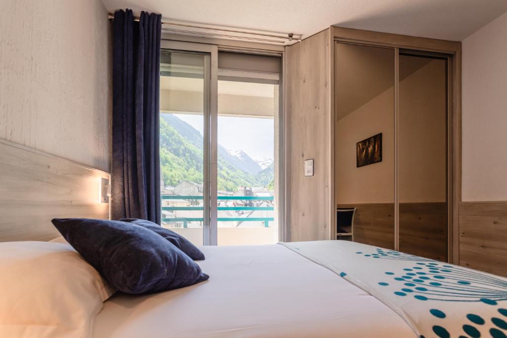 a bedroom with a bed with a large window at Hôtel-Résidence Le Lys in Cauterets