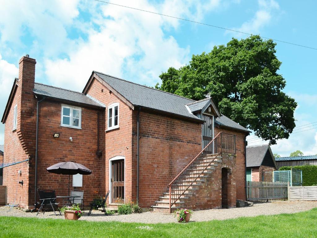 a brick building with a staircase and an umbrella at The Cider Mill Cottage in Orleton