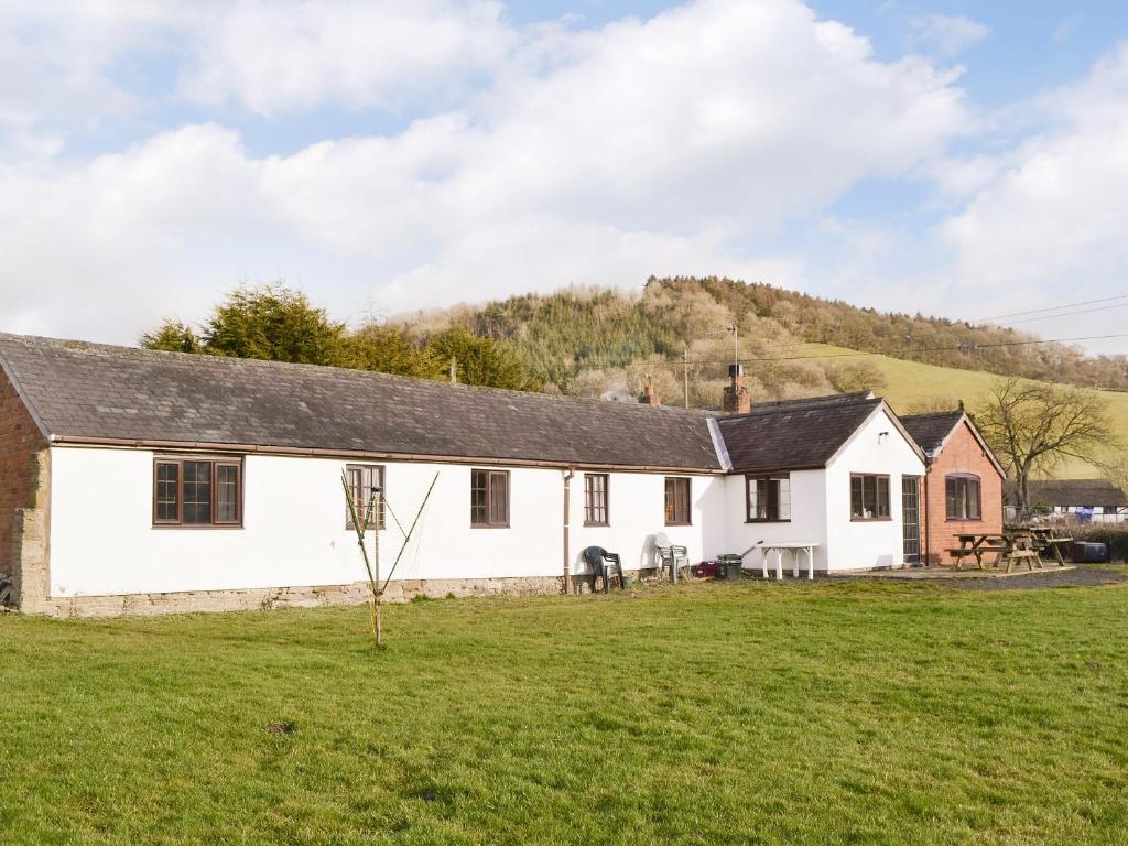 ein weißes Haus mit einem Grasfeld davor in der Unterkunft Grove Sprightly Barn in Craven Arms
