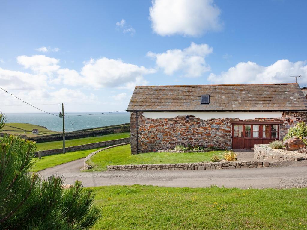 un ancien bâtiment en pierre avec l'océan en arrière-plan dans l'établissement Smugglers Retreat, à Hartland