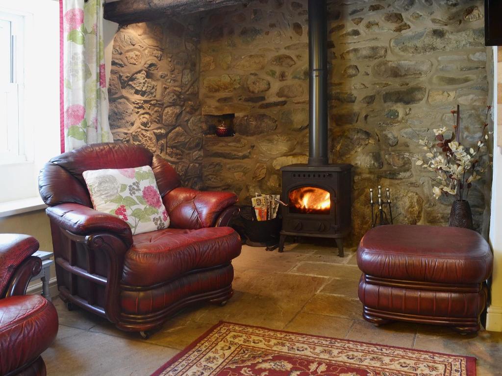 a living room with a chair and a wood stove at Cyll Y Felin Fawr 1 in Aberdaron