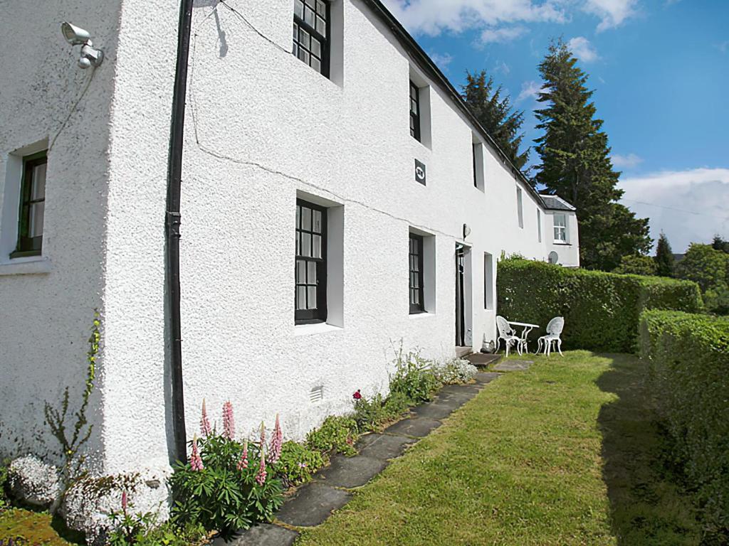 a white building with a yard and a table and chairs at Temple House West in Drumnadrochit