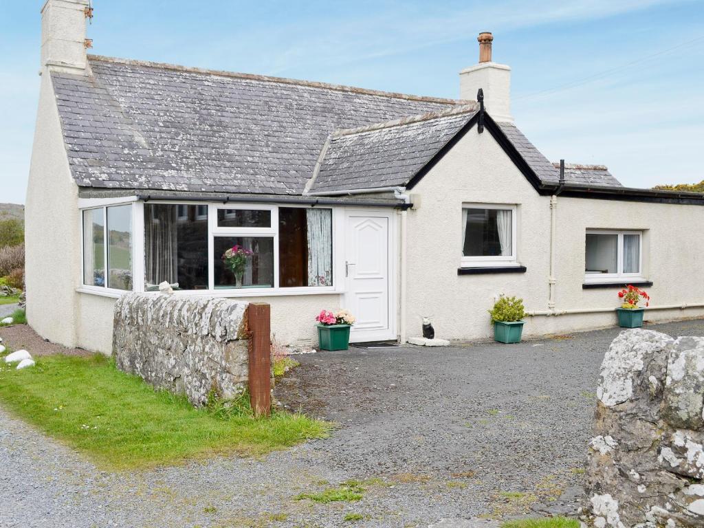 a white house with a stone wall in front of it at Knock School Cottage in Monreith