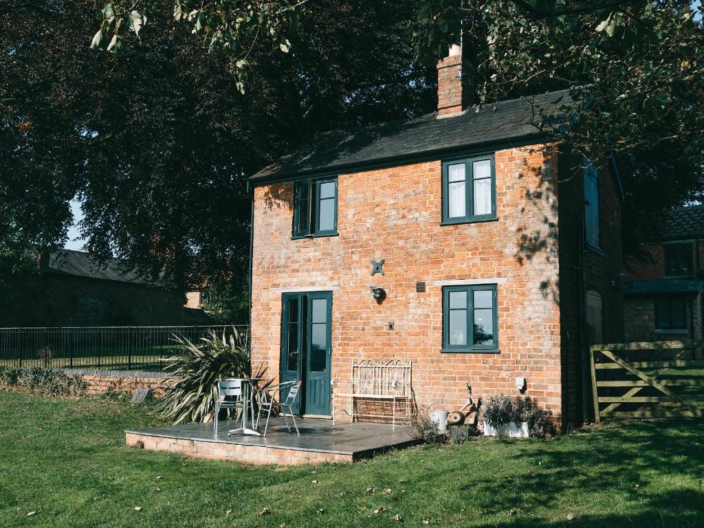 a brick house with a porch and chairs in front of it at Southfield Cottage in Braunston