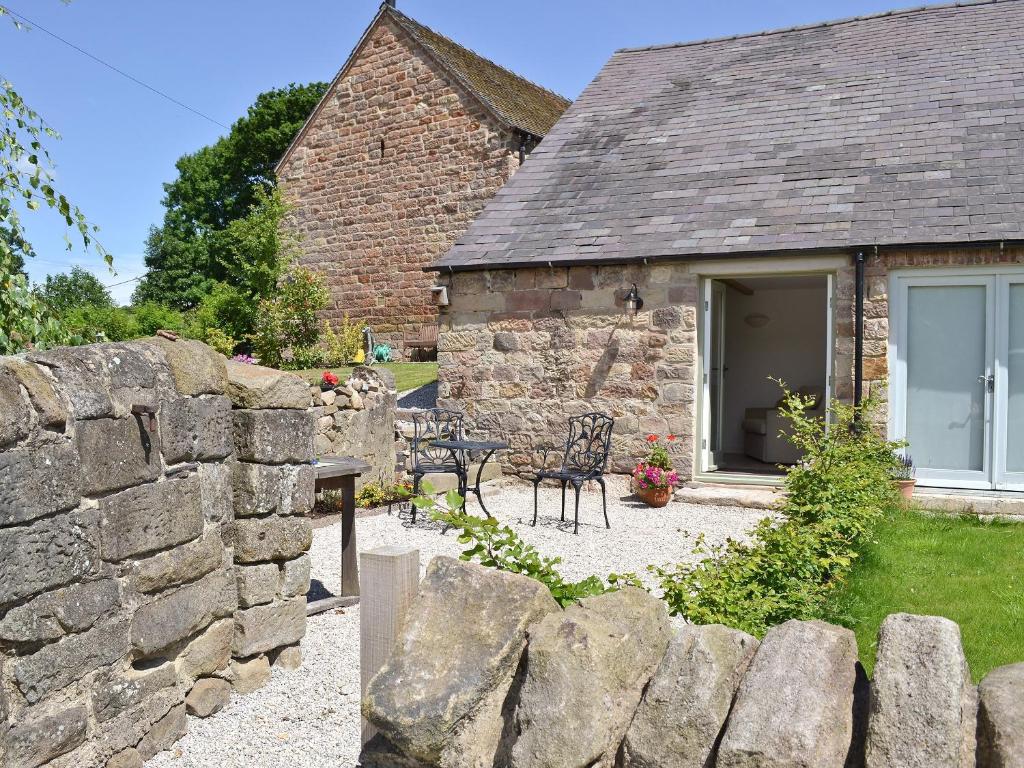 a stone house with a patio and a stone wall at The Briar in Idridgehay