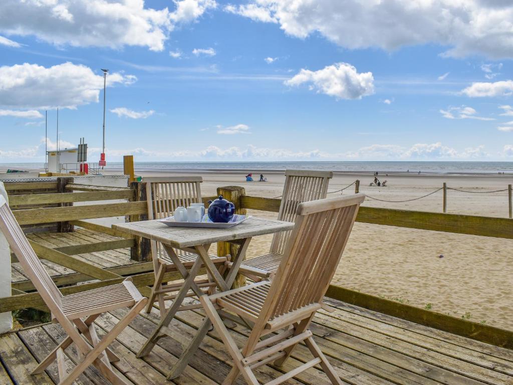 a table and chairs on a boardwalk at the beach at Seaspray in Camber