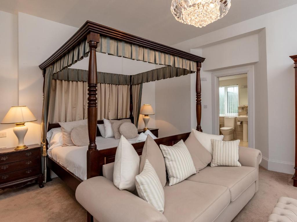 a bedroom with a four poster bed and a couch at Oddicombe, Torquay in Torquay