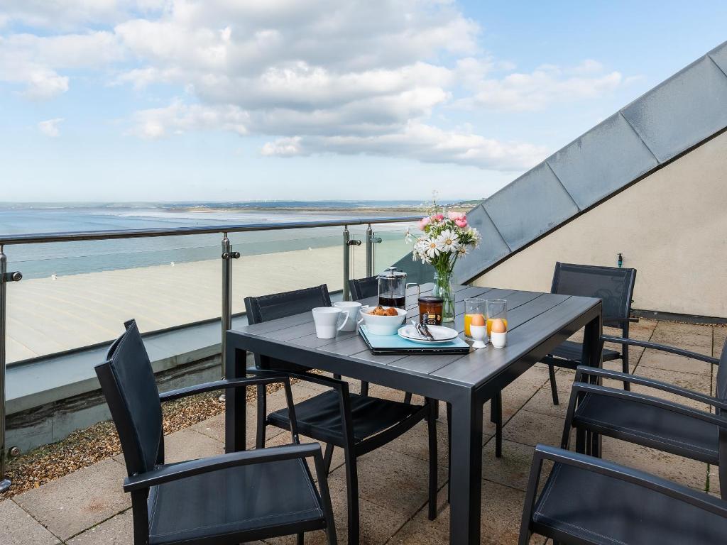 d'une table et de chaises sur un balcon avec vue sur la plage. dans l'établissement Sand Dunes, à Westward Ho