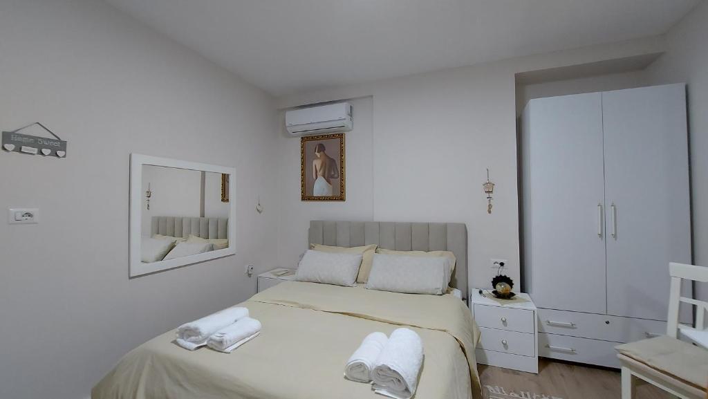a white bedroom with a bed with towels on it at Tranquil Oasis for Two in Tirana