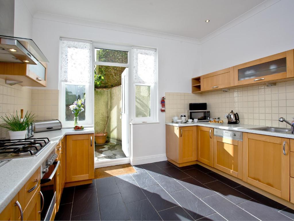 a kitchen with wooden cabinets and a large window at Quay House, Porth Beach in Saint Columb Minor