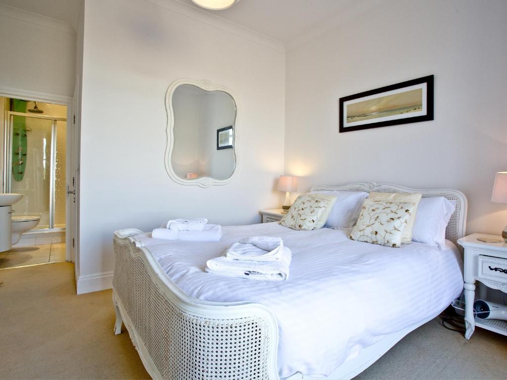 a bedroom with a white bed with a mirror on the wall at Quay House, Porth Beach in Saint Columb Minor