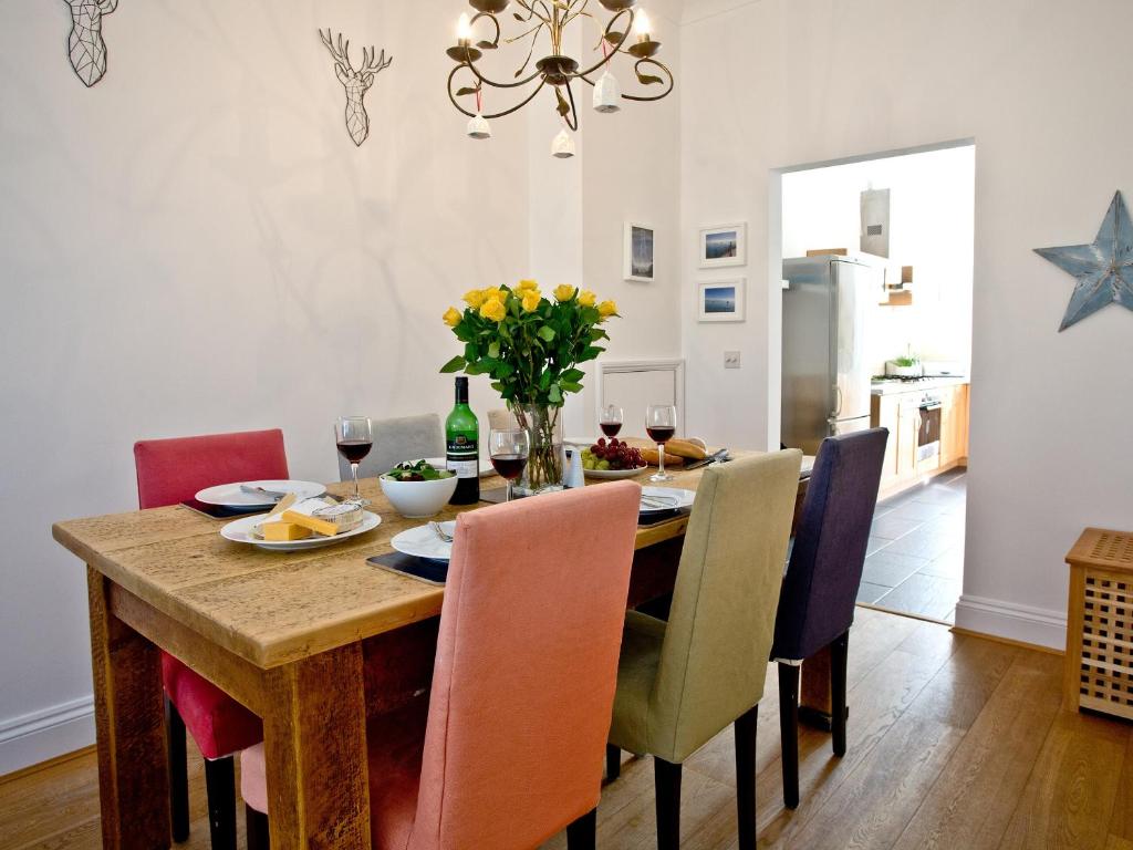 a dining room with a table with chairs and a chandelier at Quay House, Porth Beach in Saint Columb Minor