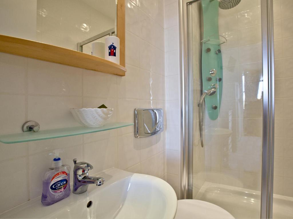 a bathroom with a sink and a shower at Quay House, Porth Beach in Saint Columb Minor