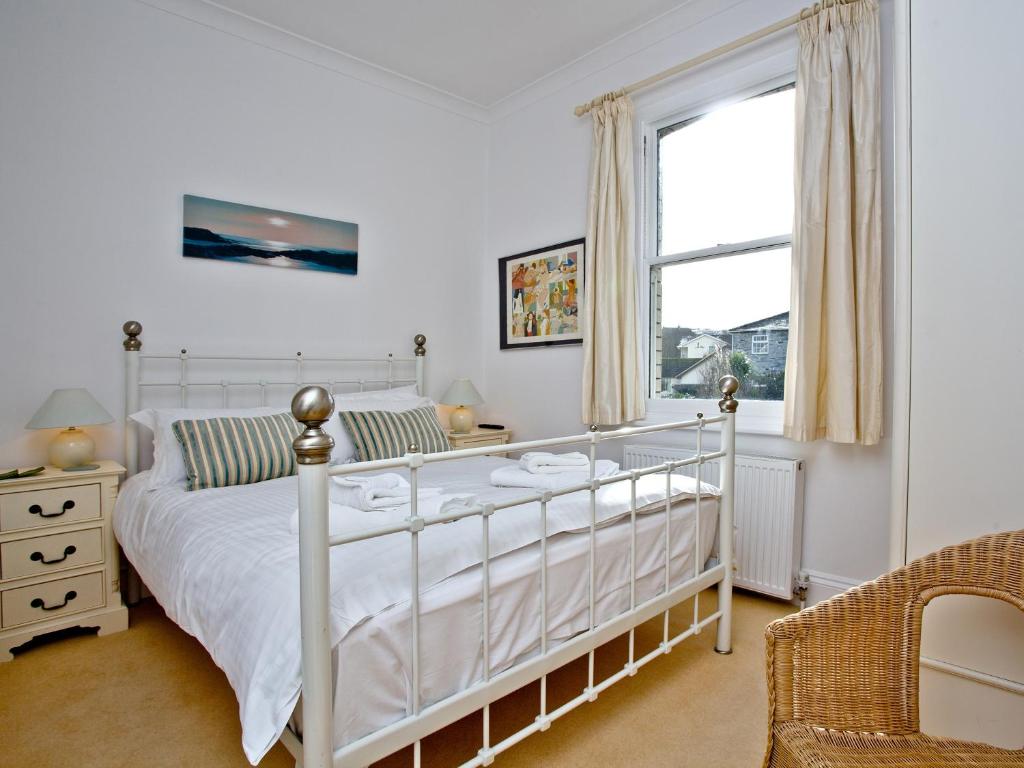 a bedroom with a white bed and a window at Quay House, Porth Beach in Saint Columb Minor