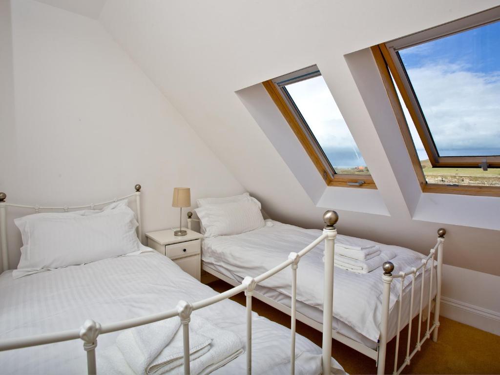 two beds in a room with two windows at Quay House, Porth Beach in Saint Columb Minor