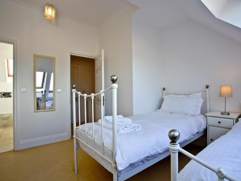a bedroom with two beds and a mirror at Quay House, Porth Beach in Saint Columb Minor