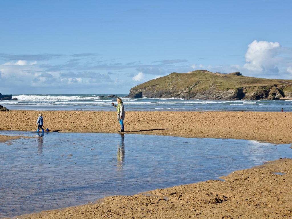 two people standing in the water on a beach at Quay House, Porth Beach in Saint Columb Minor