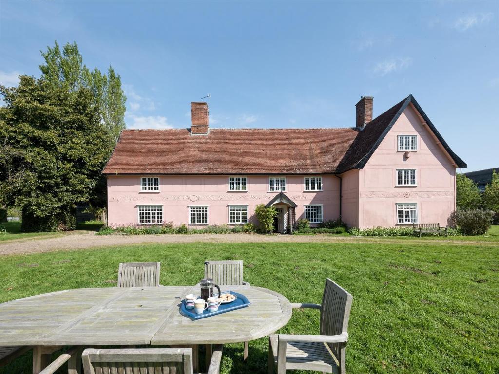 une table devant une grande maison rose dans l'établissement Cravens Manor, à Sotherton