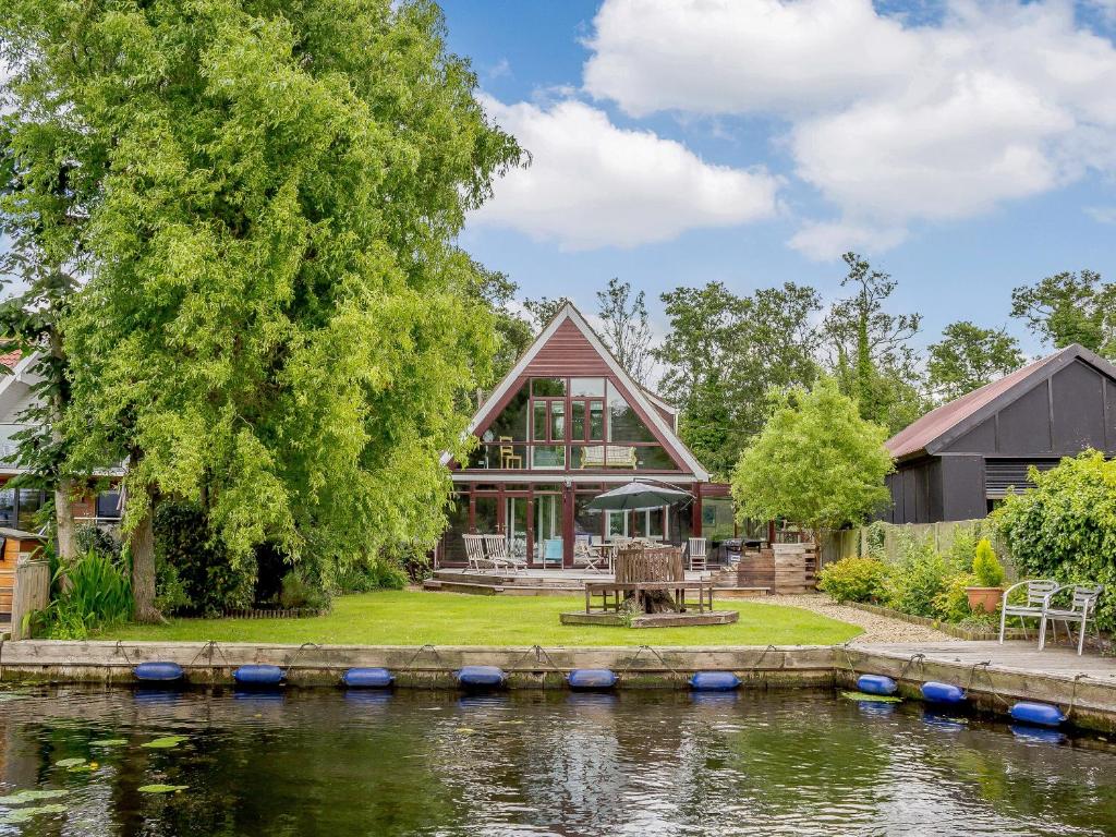 a house with a river in front of it at Silver Waters in Wroxham