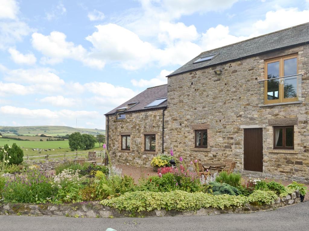 a stone house with a garden in front of it at New Park Farm - Church Cottage in Ireby