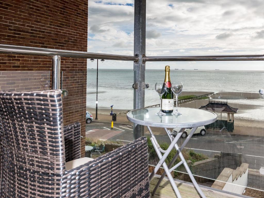 a bottle of champagne sitting on a table on a balcony at Lower Chine Apartment in Shanklin