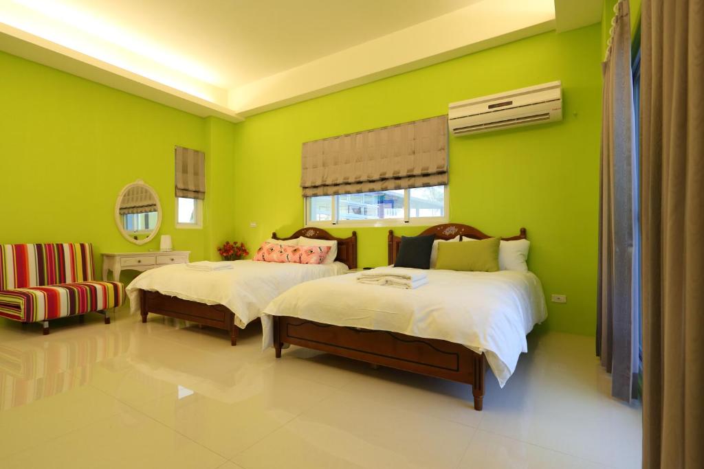 een groene slaapkamer met 2 bedden en een stoel bij Taroko Bay B&B in Xincheng