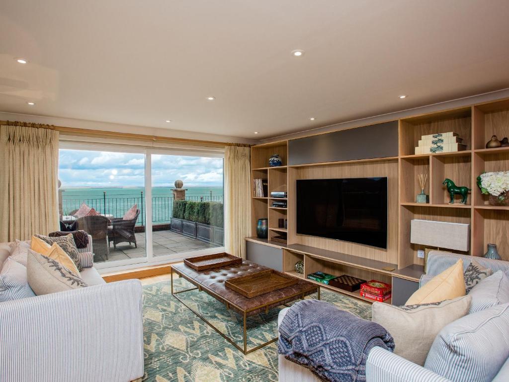 a living room with a tv and a large window at Solent View Apartment in West Cowes
