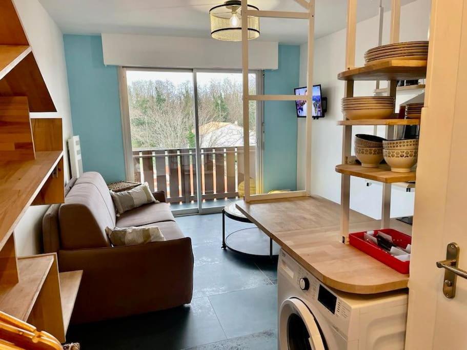 eine Küche mit einem Sofa und einem Tisch in einem Zimmer in der Unterkunft L'Acacia - 180m de la plage. in Saint-Georges-de-Didonne