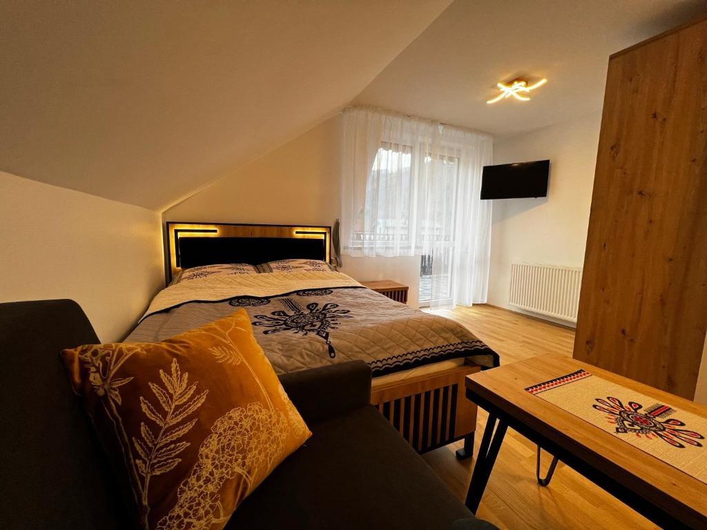- une chambre avec un lit, un canapé et une table dans l'établissement Pokoje gościnne BROKAT, à Szczyrk