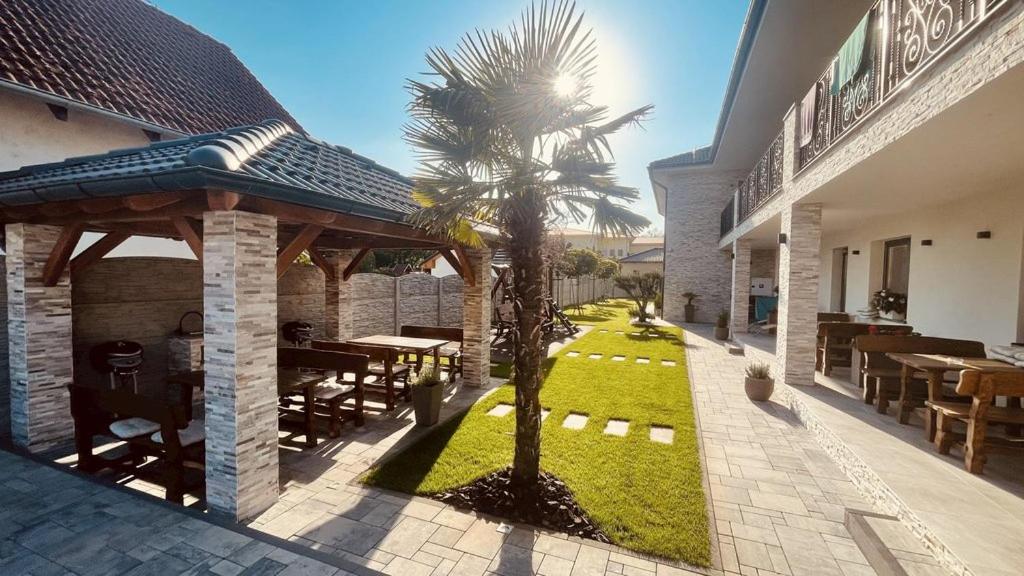 a patio of a house with a table and a palm tree at Eugen Apartmán in Veľký Meder