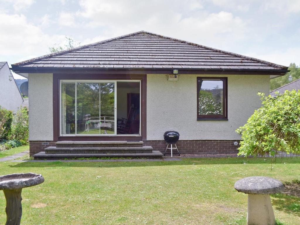 a small white house with a window and a grill at Kingfisher Cottage in Pitlochry