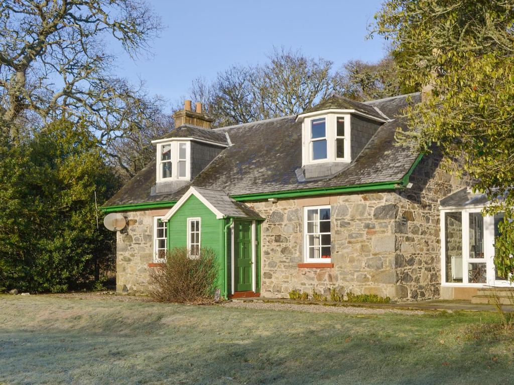 an old stone house with a green door at Kennels Cottage - Beaufort Estate in Belladrum
