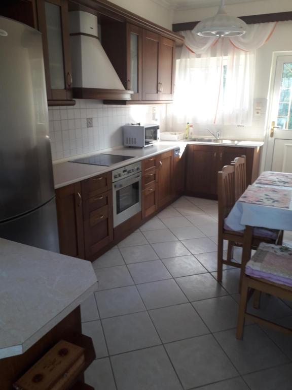 uma cozinha com armários de madeira e piso em azulejo branco em 150ευρώ η μέρα em Oropós