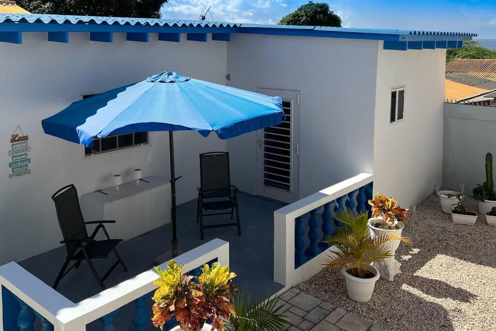 patio z niebieskim parasolem, stołem i krzesłami w obiekcie Hofi Celia w mieście Blue Bay