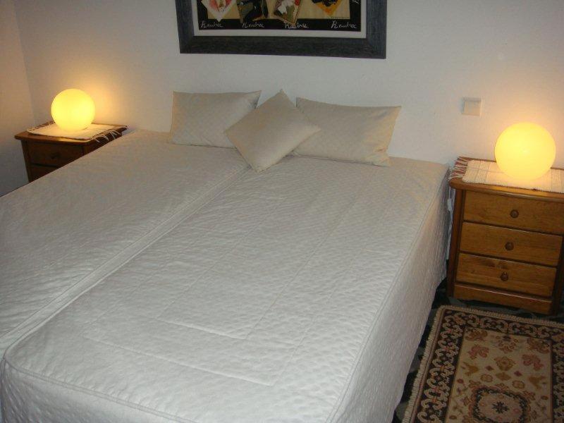 a bedroom with a white bed with two night stands at Quarto pequeno 515 do Monte dos Arneiros in Lavre
