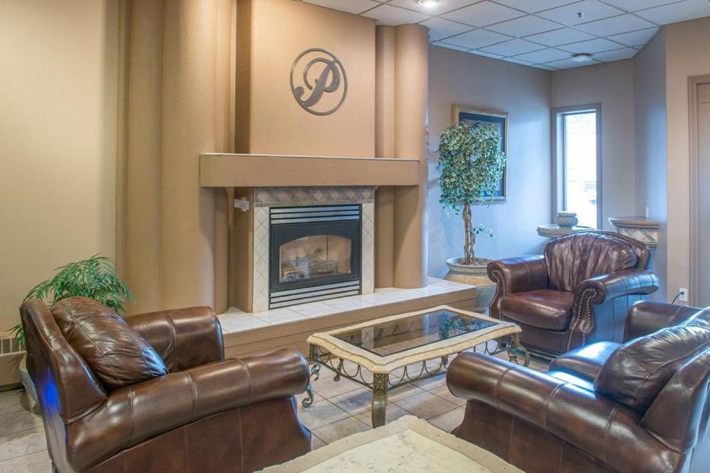 a lobby with leather chairs and a fireplace at Prime Hotel in Fort McMurray