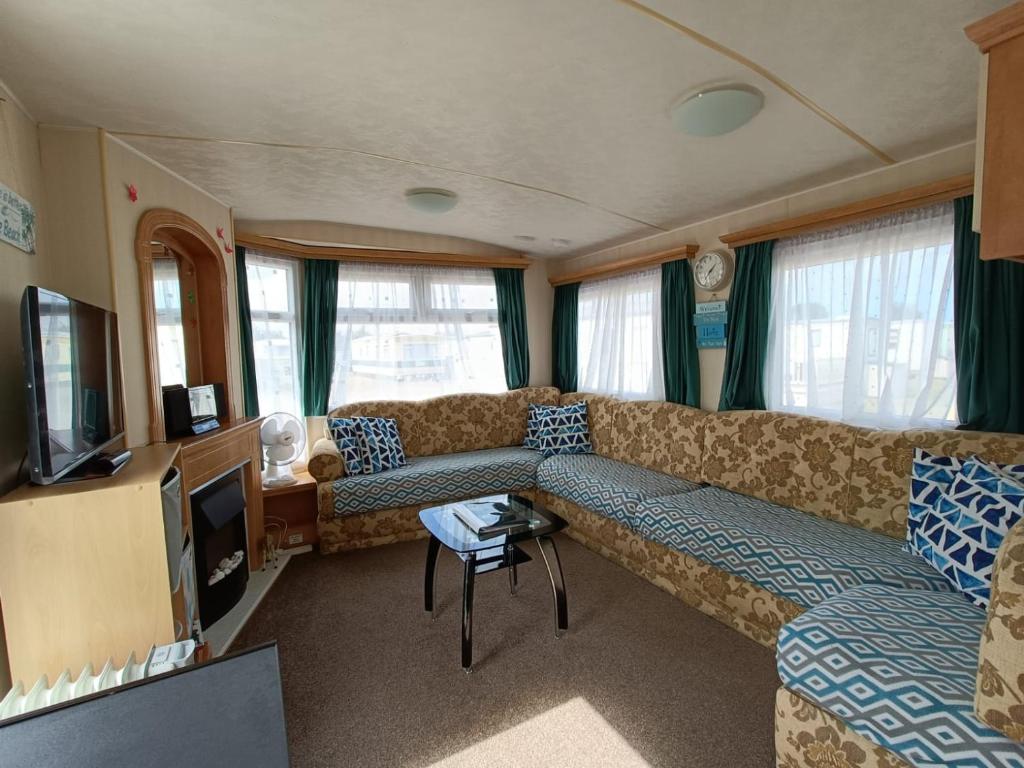 uma sala de estar com um sofá e uma televisão em Pet friendly Holiday Caravan sleeps 5 em Hemsby