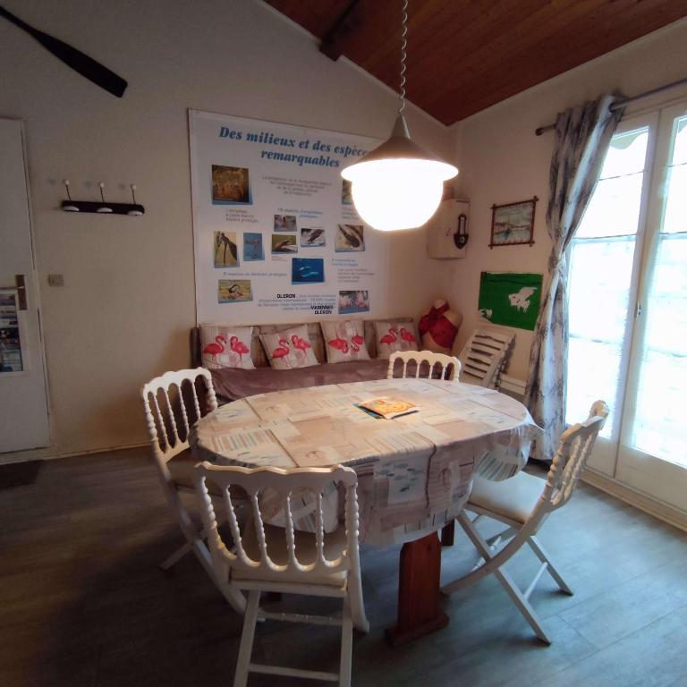 una mesa de comedor y sillas en una habitación en Appartement cosy à quelques pas de la plage de la Rémigeasse en Dolus d'Oléron