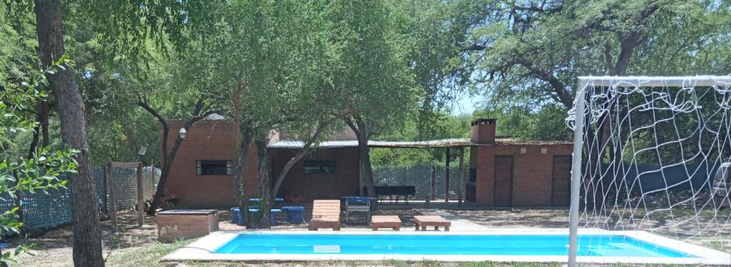 a swimming pool with a net and a house at Finca La Huella II in Santiago del Estero