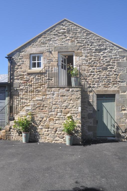 una casa de piedra con una puerta y dos macetas en The Hay Loft Southlands Farm en Gunnerton
