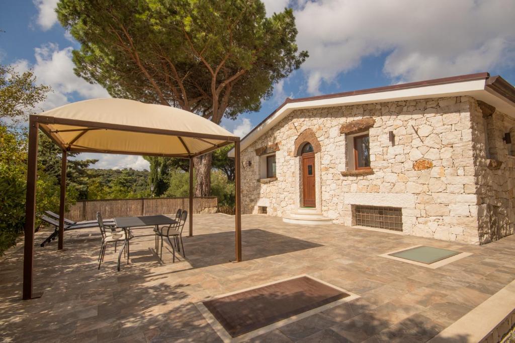 un patio con mesa y sombrilla en Villa Corbezzolo (Country House), en Dorgali