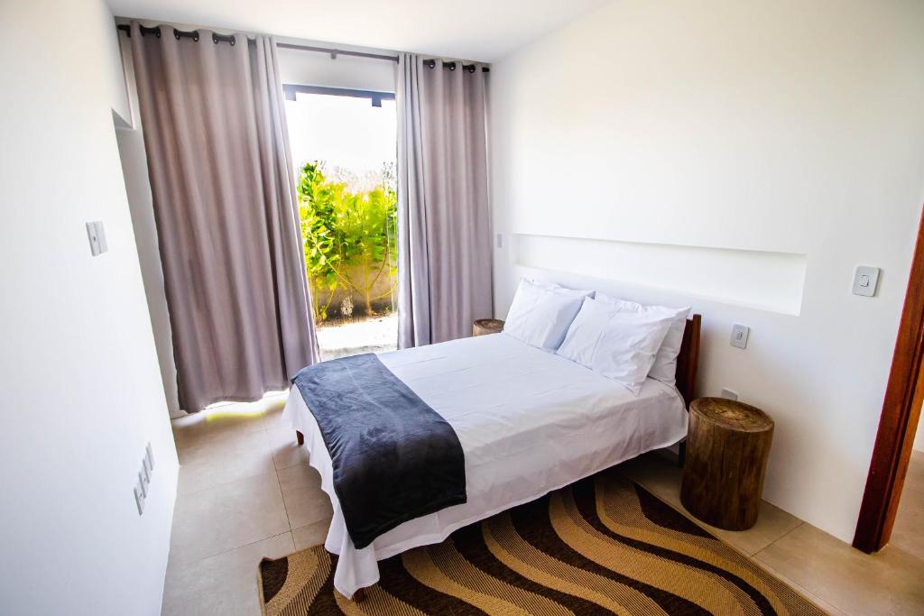 um quarto com uma cama e uma grande janela em Casa nova completa a poucos passos da Praia do Mutà em Porto Seguro