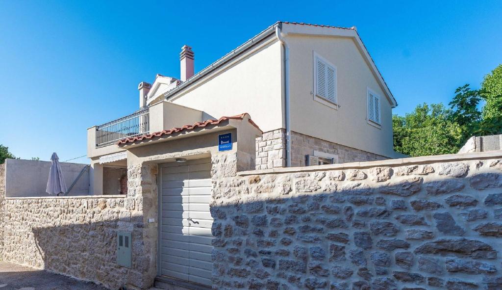 una casa con una pared de piedra y un garaje en MY DALMATIA - Holiday home near the beach Marijanka en Petrcane