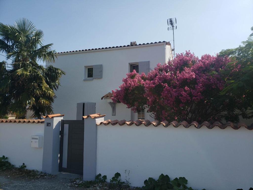 una casa blanca con una valla y flores púrpuras en Chambre Zen à la campagne, en Marennes