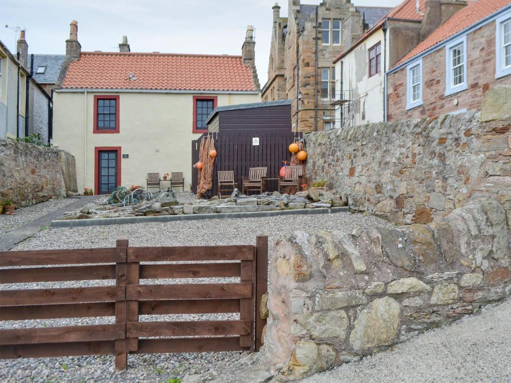 a stone wall with a wooden fence in front of some buildings at Low Tide in Cellardyke