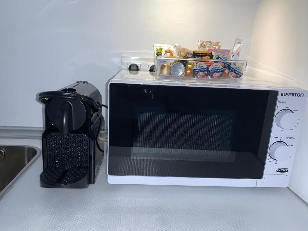 un microondas sentado en un mostrador de cocina con un objeto negro en VEROMA PISOS, en Granada